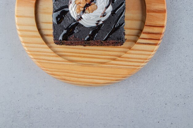 Fetta di gustoso brownie al cioccolato con crema sul piatto di legno. Foto di alta qualità