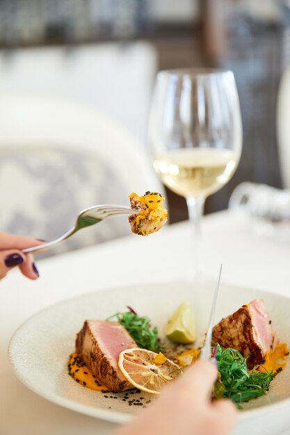 Fetta di gustoso pasto di tonno con bicchiere di vino bianco al ristorante