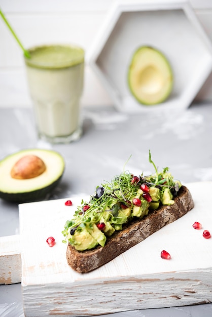 Fetta di pane con pasta di avocado e bicchiere di frullato