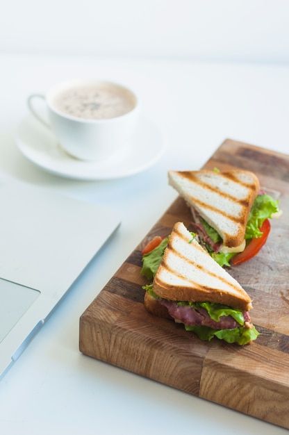 Fetta di panini al prosciutto e tazza di caffè sullo sfondo