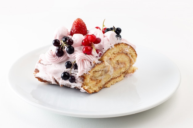 Fetta di rotolo di vista frontale con mirtilli crema e fragola all'interno del piatto bianco su bianco