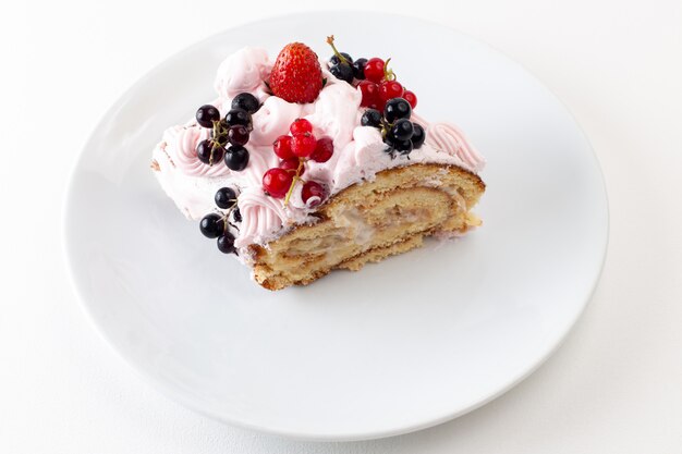 Fetta di rotolo di vista frontale con mirtilli crema e fragola all'interno del piatto bianco su bianco