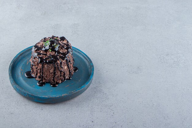 Fetta di torta al cioccolato decorata con sciroppo su piatto blu