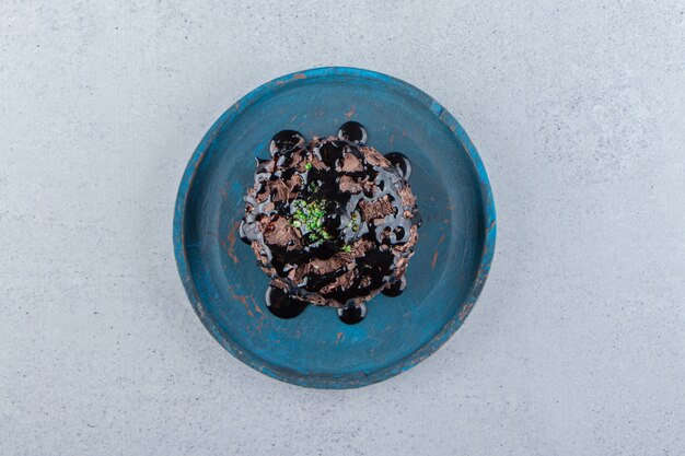 Fetta di torta al cioccolato decorata con sciroppo sul piatto blu. Foto di alta qualità