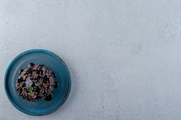 Fetta di torta al cioccolato decorata con sciroppo sul piatto blu. Foto di alta qualità