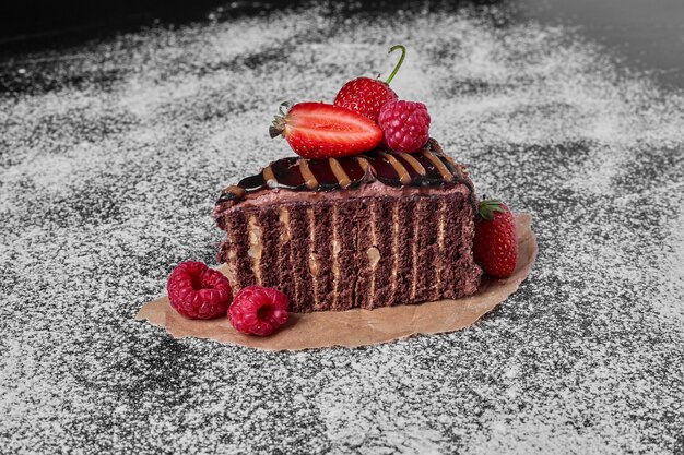 Fetta di torta al cioccolato su un piatto di legno.