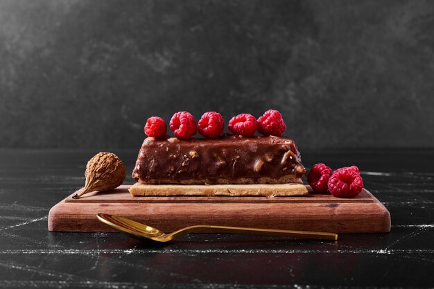 Fetta di torta al cioccolato sul piatto di legno.