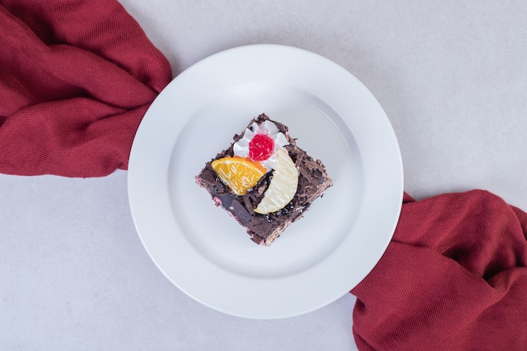 Foto gratuito fetta di torta al cioccolato sulla zolla bianca con tovaglia rossa.