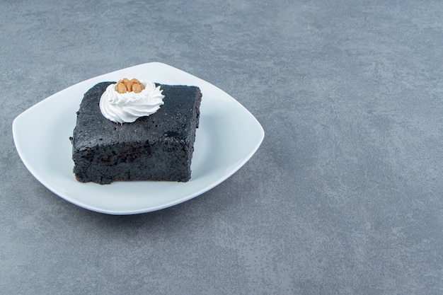 Fetta di torta brownie sul piatto bianco.