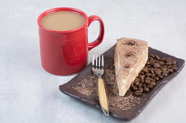 Fetta di torta con chicchi di caffè e tazza di caffè