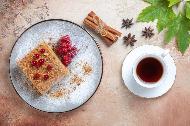 Fetta di torta vista dall'alto con bacche rosse e tè in luce