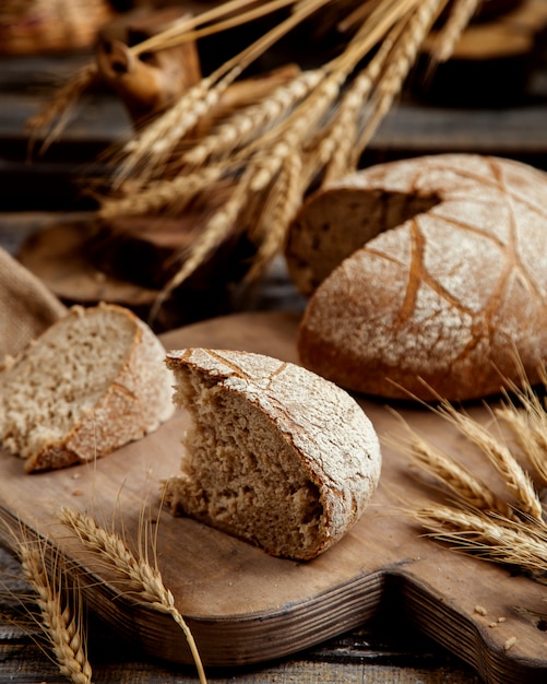 Fetta organica del pane nero disposta sul bordo di legno nello stile rustico