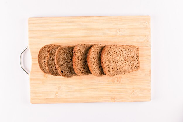 Fette del pane scuro su un bordo di legno isolato