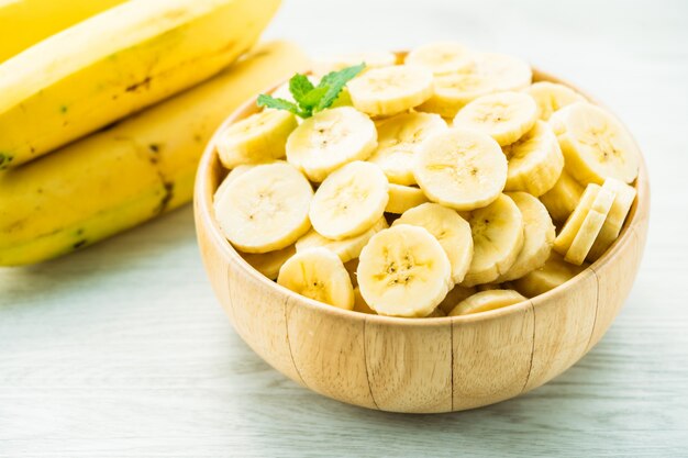 Fette di banana gialla cruda in ciotola di legno