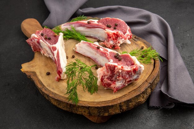 Fette di carne cruda vista frontale con verdure e pepe su sfondo scuro foto a colori di mucca carne cruda di pollo animale