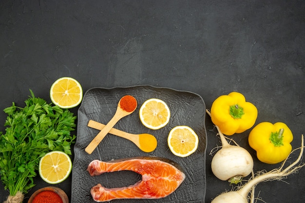 Fette di carne fresca vista dall'alto con limone verde e condimenti su sfondo scuro