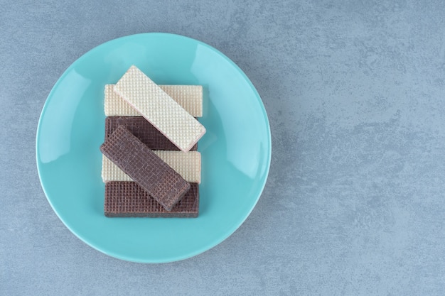 Fette di cialda al cioccolato e caramello sul piatto blu.