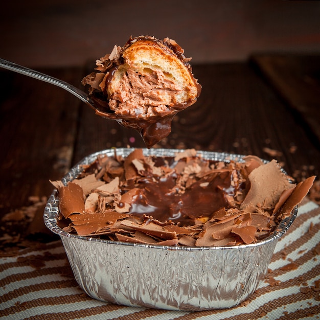 fette di cioccolato con cucchiaio e torta in un contenitore di alluminio