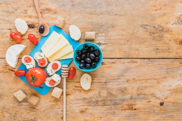 Fette di formaggio, pomodori, pane e olive sul tavolo di legno