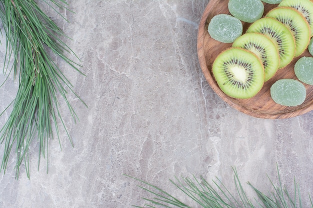 Fette di kiwi e marmellate sul piatto di legno con ramo.