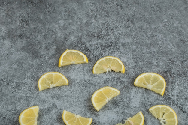 Fette di limone acido su una superficie grigia.