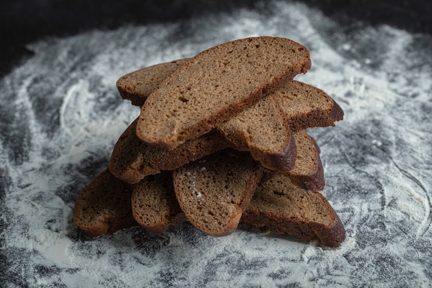 Fette di pane appena sfornate Brown su sfondo di farina bianca.