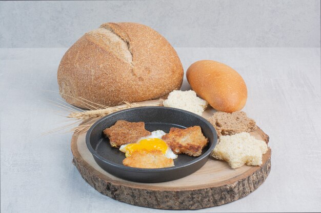 Fette di pane bianco e marrone con uovo fritto sul piatto di legno.