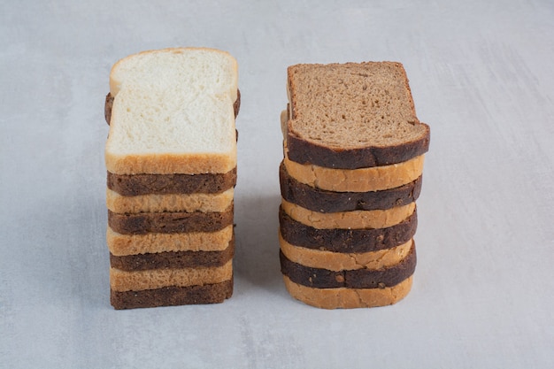 Fette di pane bianco e marrone fresco su fondo di marmo.