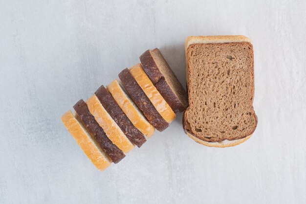 Fette di pane bianco e marrone fresco su fondo di marmo.