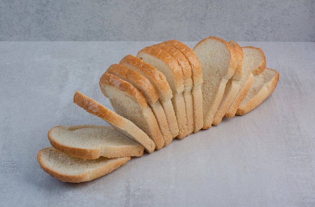 Fette di pane bianco fresco su sfondo marmo.