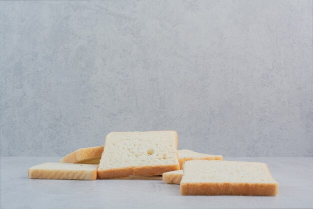 Fette di pane bianco fresco su sfondo marmo.