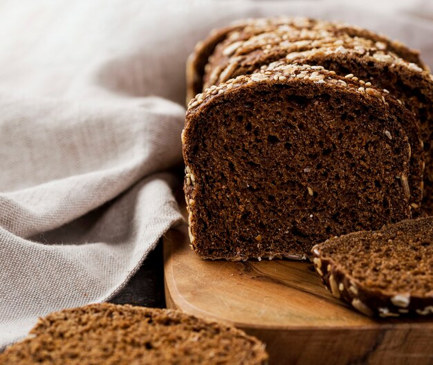 Fette di pane del primo piano sul bordo di legno con il panno