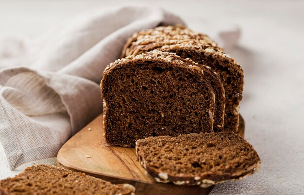 Fette di pane di vista frontale con i grani sul bordo di legno