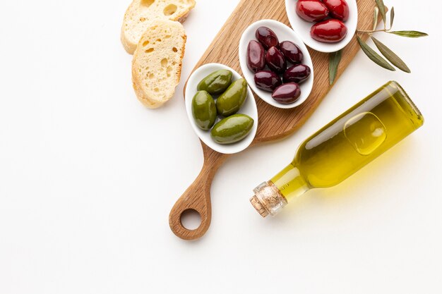 Fette di pane e olive verdi rosse viola con la bottiglia di olio d'oliva