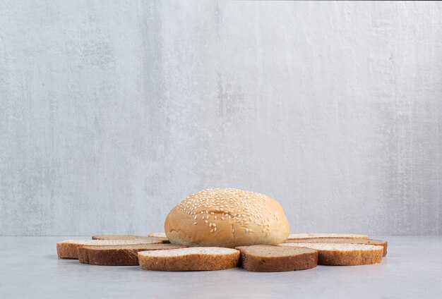 Fette di pane e panino con semi di sesamo su sfondo blu. Foto di alta qualità