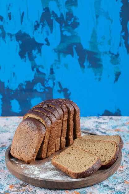 Fette di pane integrale con farina su tavola rotonda di legno.