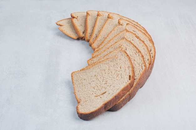 Fette di pane integrale fresco su sfondo marmo.