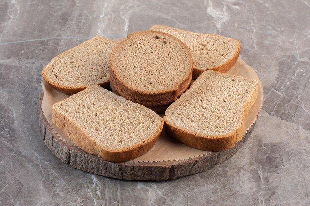 Fette di pane integrale su una tavola di legno su fondo marmo. Foto di alta qualità