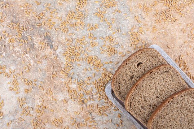 Fette di pane nero con chicchi d'orzo su superficie in marmo