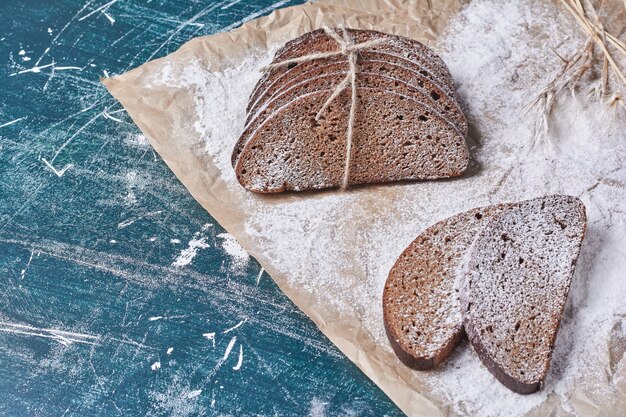 Fette di pane nero con etichetta su di loro sul tavolo blu.