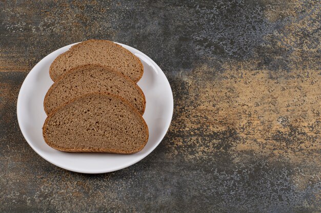 Fette di pane nero di segale sul piatto bianco