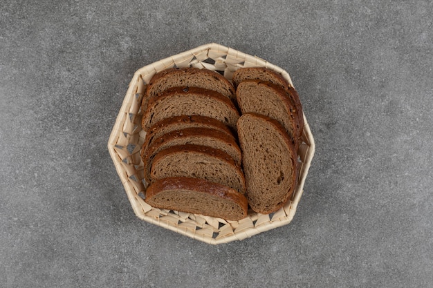 Fette di pane nero in cestino di legno.