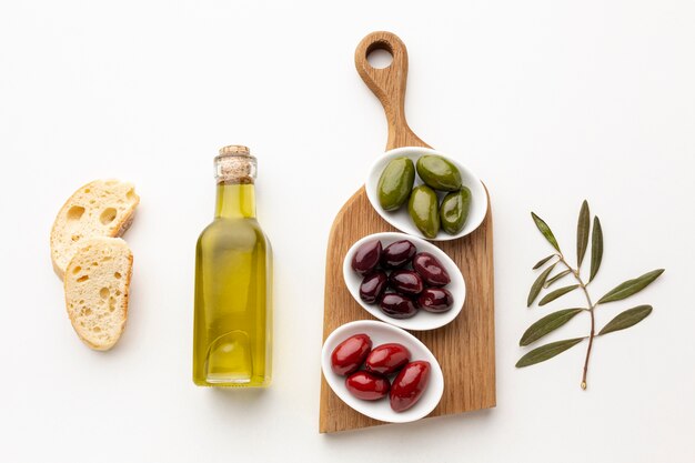 Fette di pane piatte e olive verdi rosso porpora con bottiglia di olio d'oliva