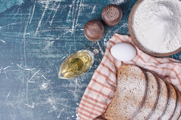 Fette di pane scuro con uova sul tavolo blu.