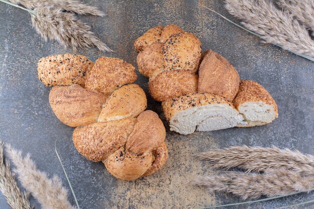 Fette di pane strucia e fascio di gambi di grano su superficie di marmo