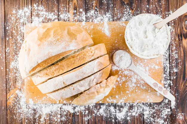 Fette di pane sul tagliere di legno si spargono con la farina