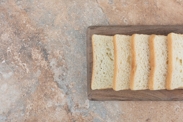 Fette di pane tostato bianco sulla tavola di legno