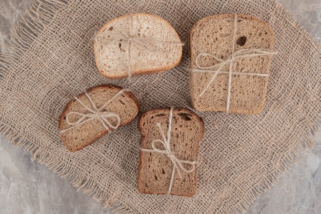 Fette di pane vario legate con una corda sulla superficie in marmo. Foto di alta qualità