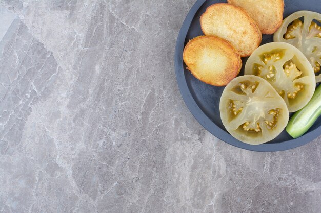 Fette di patate fritte e pomodori marinati sul piatto.