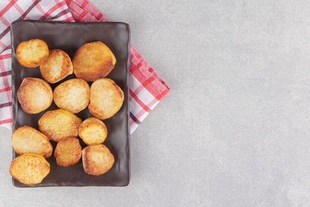 Fette di patate fritte sul piatto marrone.